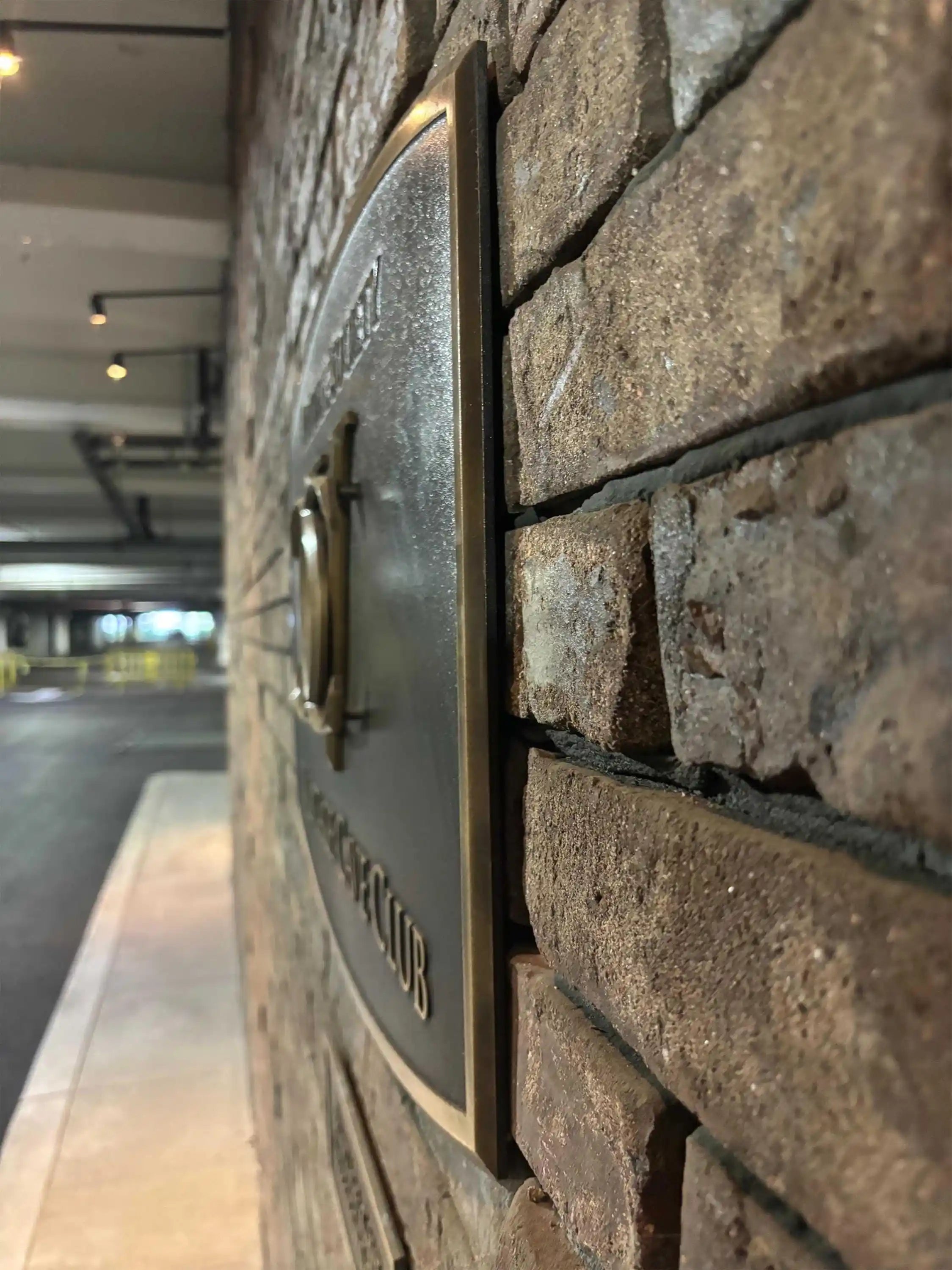 Brass plaque on a stone wall with 'Private Club' text, blurred indoor background