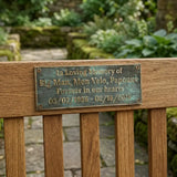 Bronze Memorial plaque in Wooden bench and plaque in memory of a pet named 'Big Man, Mon Velo, Papouné' in a garden setting.