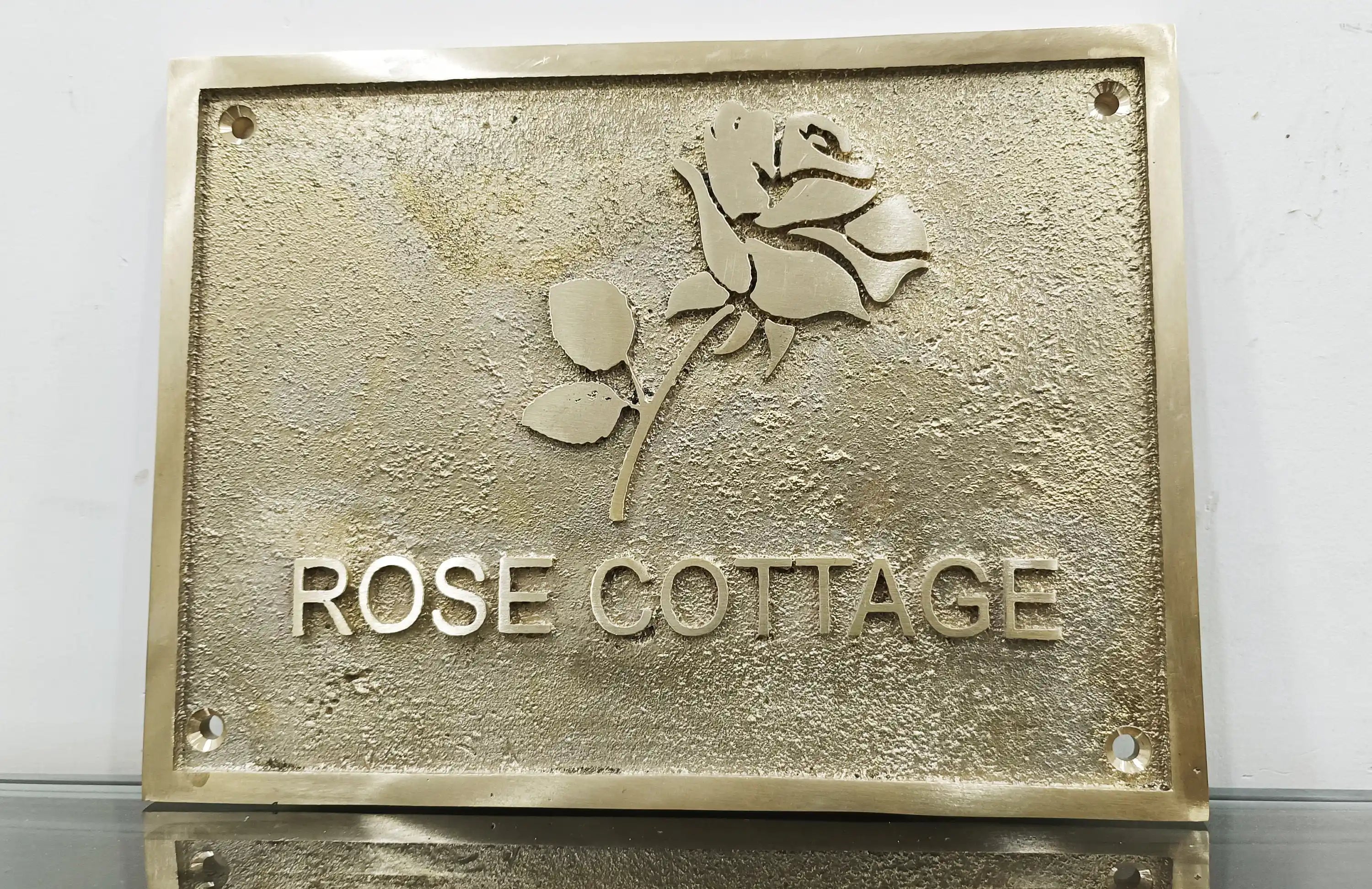 Brass plaque with 'Rose Cottage' and a rose design on a white background