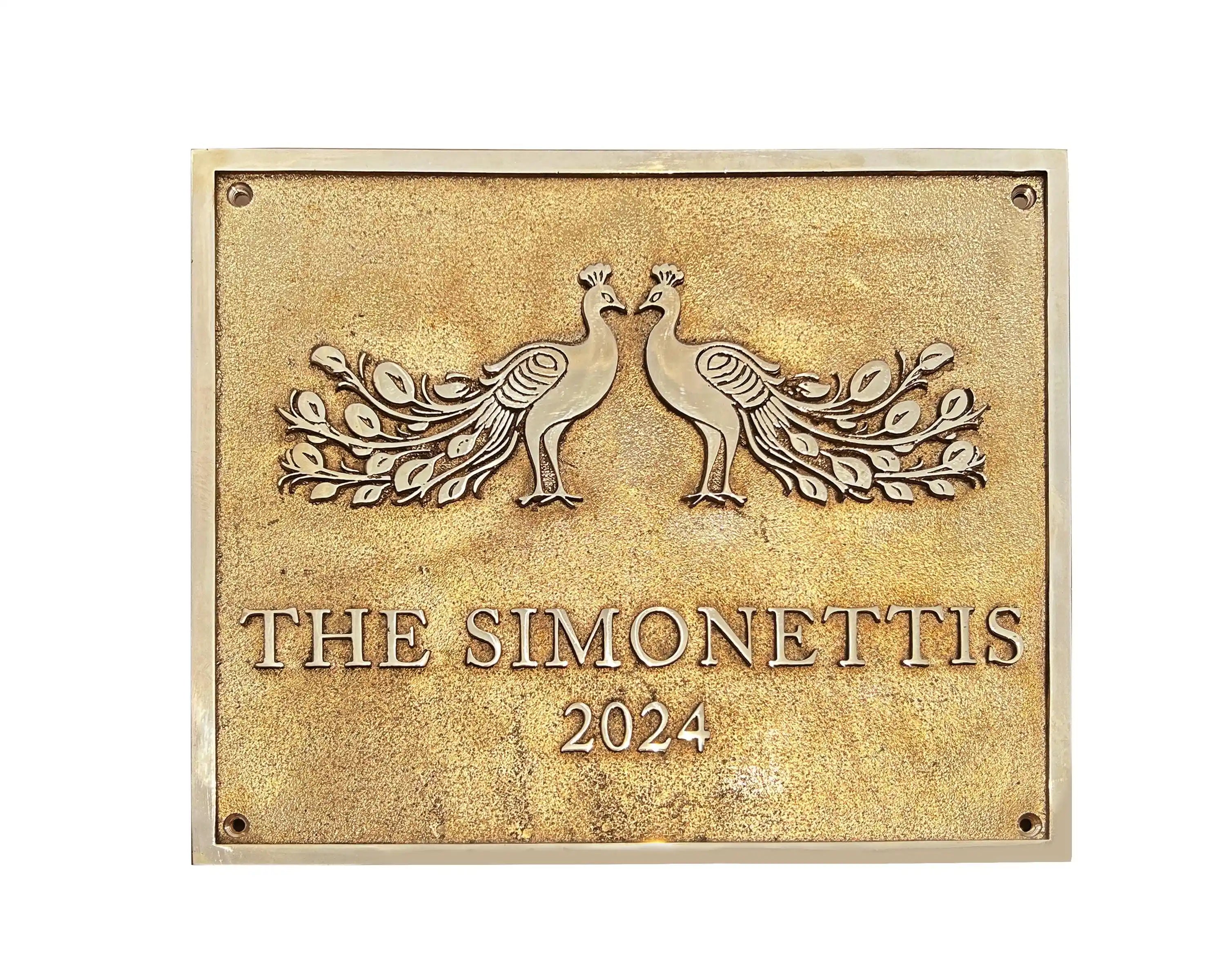Decorative plaque with peacock design and 'The Simonettis 2024' text on a gold background