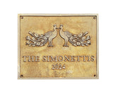 Decorative plaque with peacock design and 'The Simonettis 2024' text on a gold background