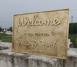 Decorative welcome sign for Justin & Sarah with a rustic finish, placed outdoors.