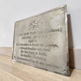 Brass memorial plaque with engraved text on a wooden surface