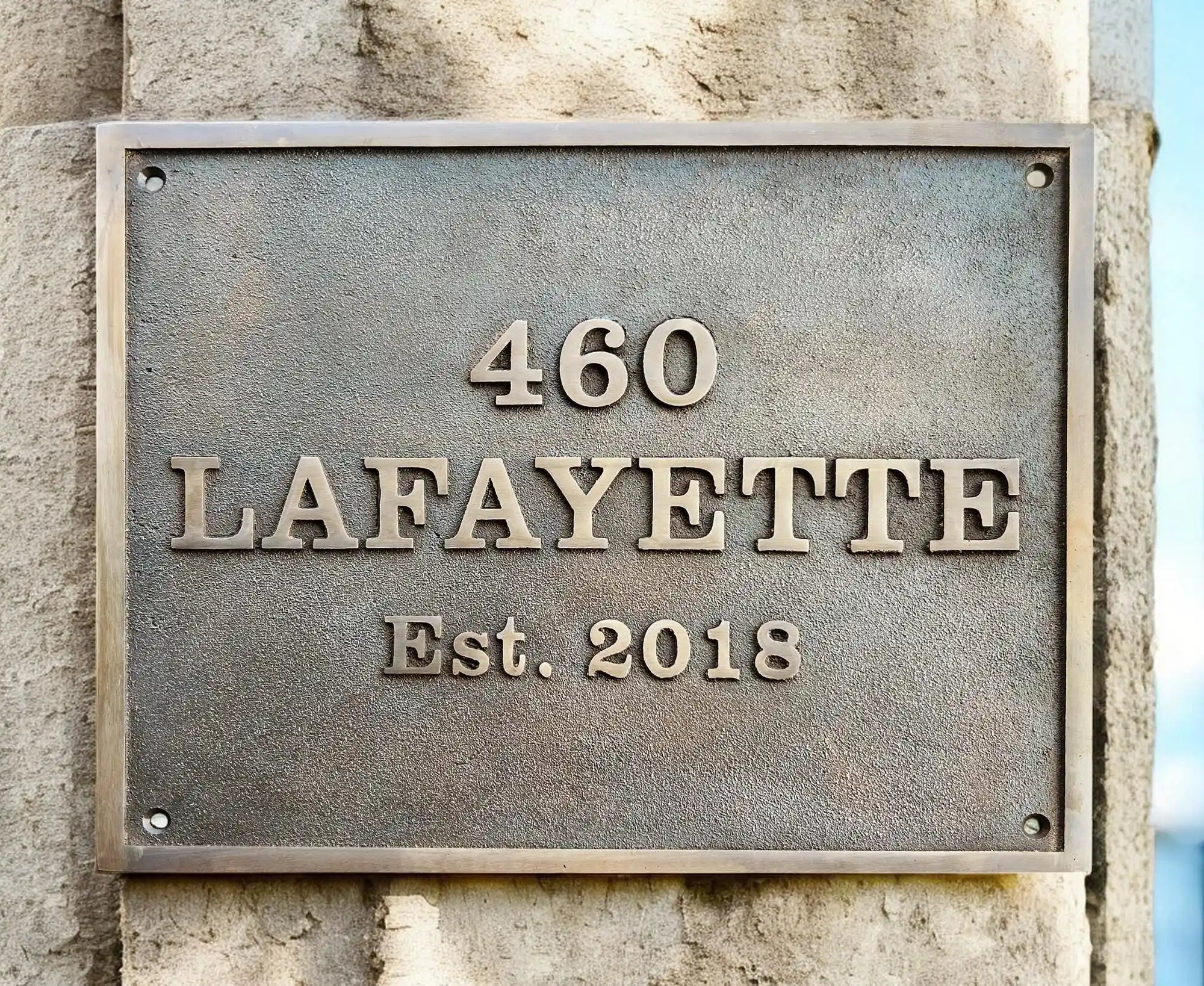 Metal plaque with '460 Lafayette Est. 2018' on a stone wall
