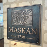 Metal plaque with 'MASKAN 1730' on a textured wall