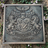 Bronze metal plaque with a coat of arms and 'ALI MAHABOOB' text, surrounded by greenery.