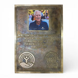 Bronze plaque with engraved text and a photo of a man, on a white background