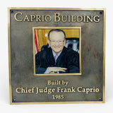 Plaque with a photo of Chief Judge Frank Caprio and text 'Caprio Building Built by Chief Judge Frank Caprio 1985'.