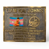 Bronze plaque with engraved text and a photo of a person, on a white background