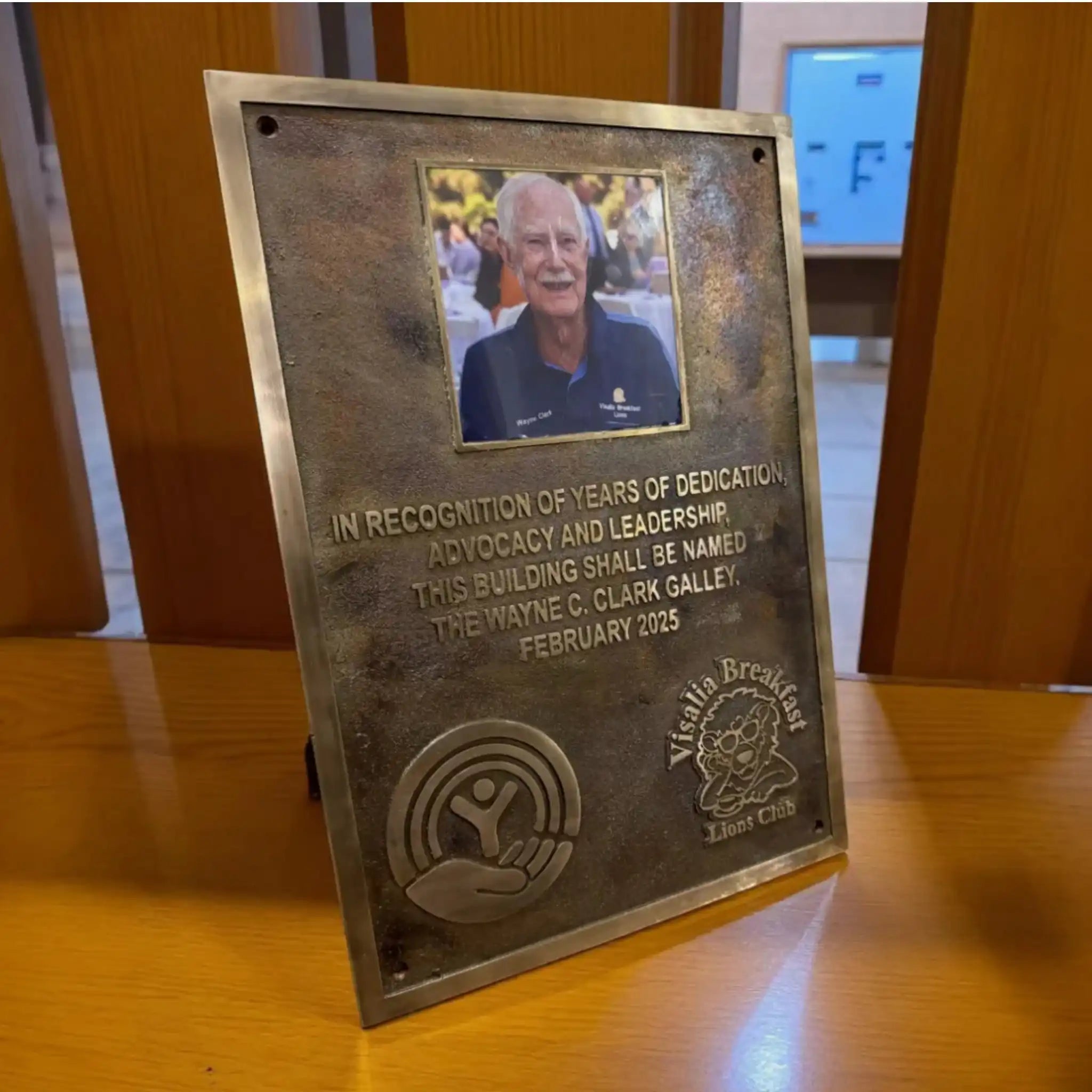 Bronze plaque with a photo of a man and engraved text on a wooden surface