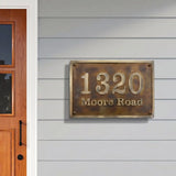 House number sign '1320 Moore Road' on a gray wall next to a wooden door.