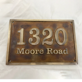 Bronze house number sign with '1320 Moore Road' on a white background