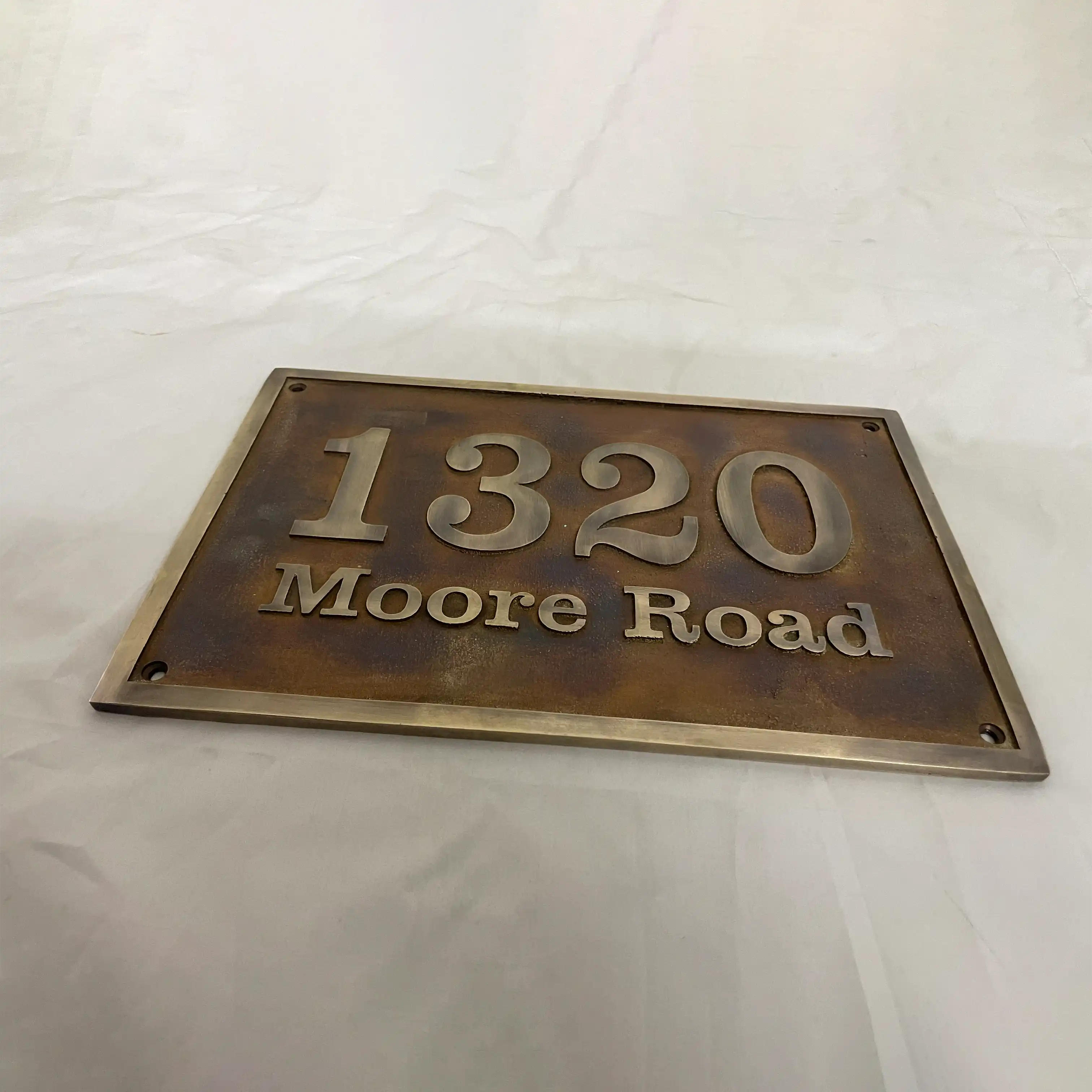 Bronze house number sign with '1320 Moore Road' on a white background