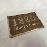 Bronze house number sign with '1320 Moore Road' on a white background