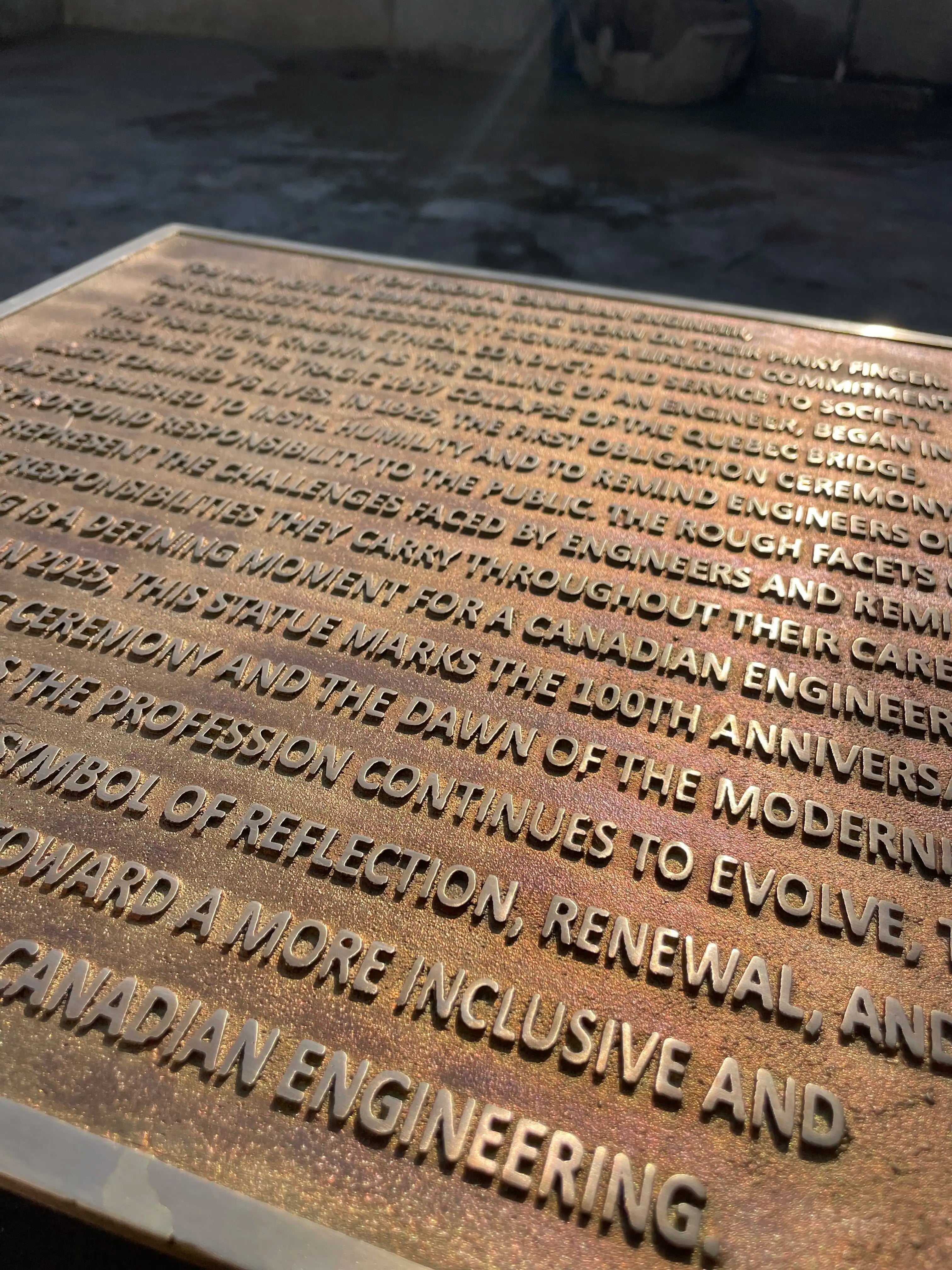 Bronze plaque with engraved text on a dark background