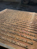Bronze plaque with engraved text on a dark background