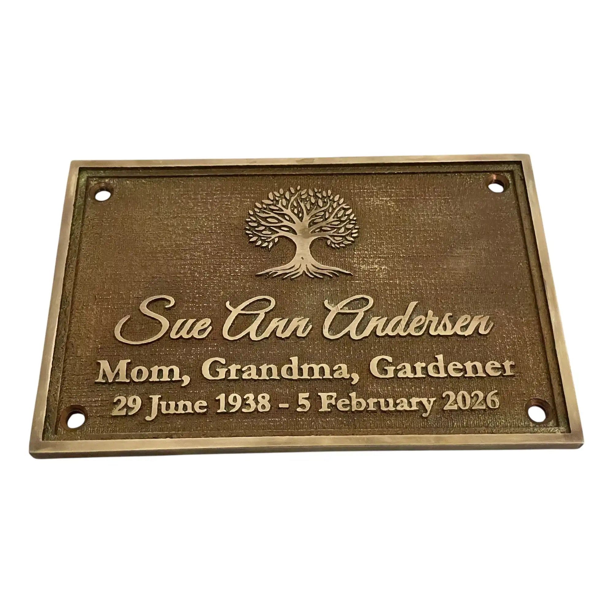 Bronze memorial plaque with engraved text and tree design on a white background