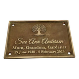 Bronze memorial plaque with engraved text and tree design on a white background