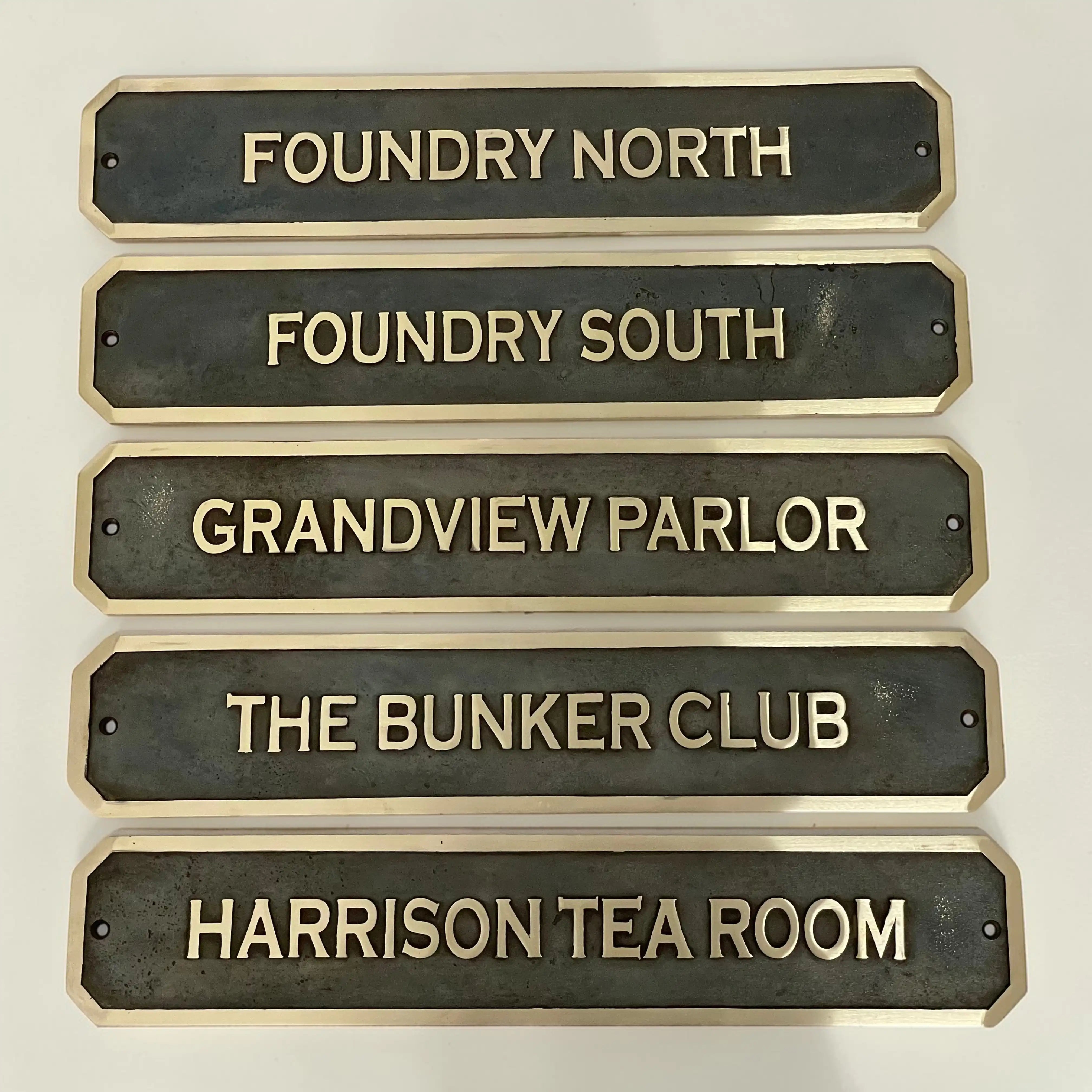 Set of bronze nameplates with gold text on a white background