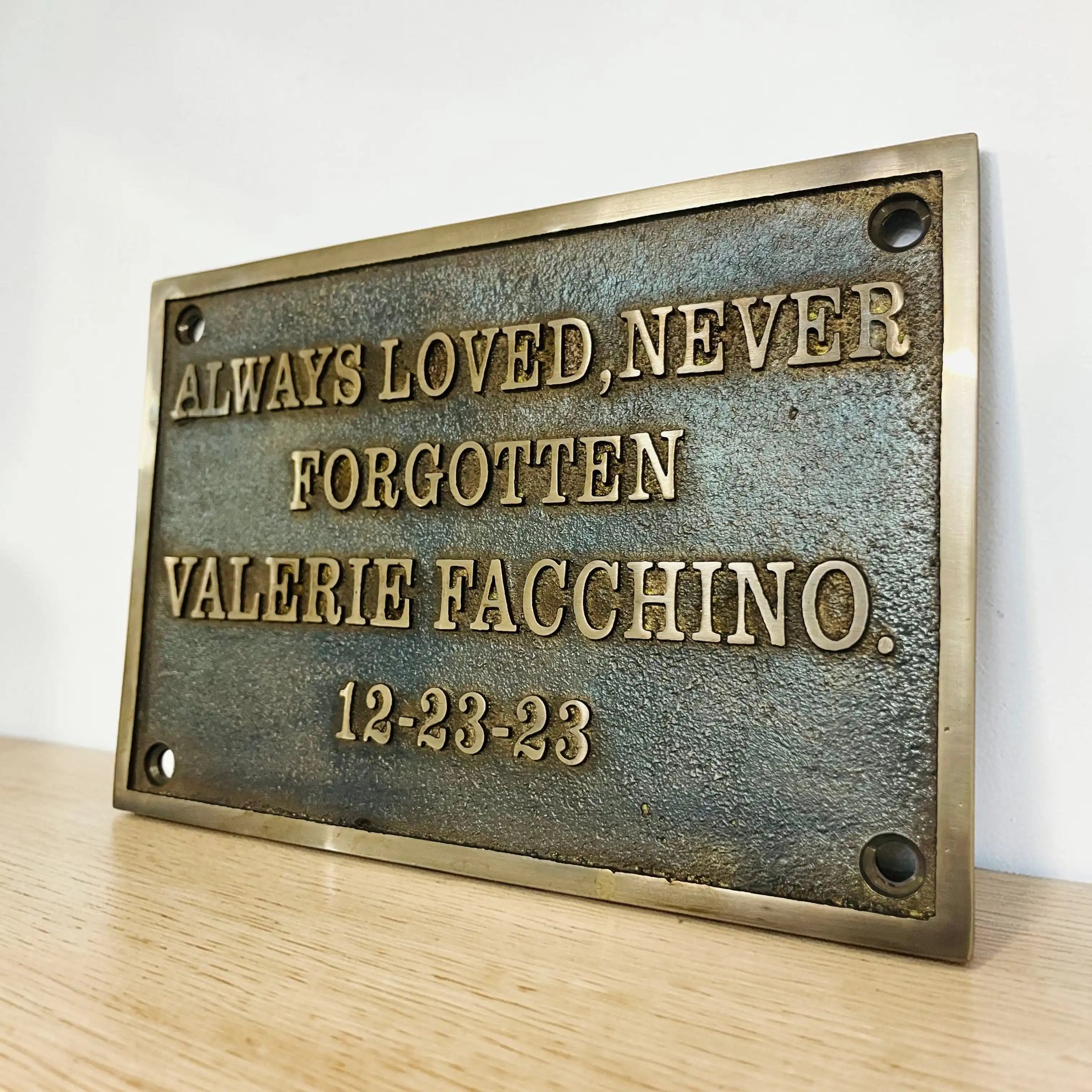 Bronze plaque with engraved text on a wooden surface