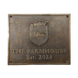 Bronze plaque with crest and 'The Farmhouse Est. 2023' text on a white background