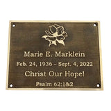 Bronze plaque with engraved text and floral design on a white background