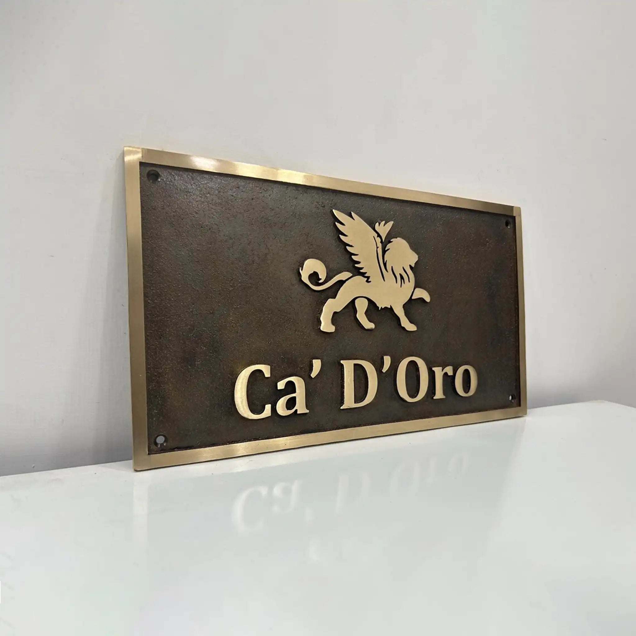 Custom Bronze sign with 'Ca' D'Oro' and a lion emblem on a white surface.