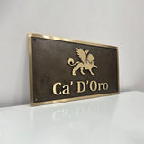 Custom Bronze sign with 'Ca' D'Oro' and a lion emblem on a white surface.