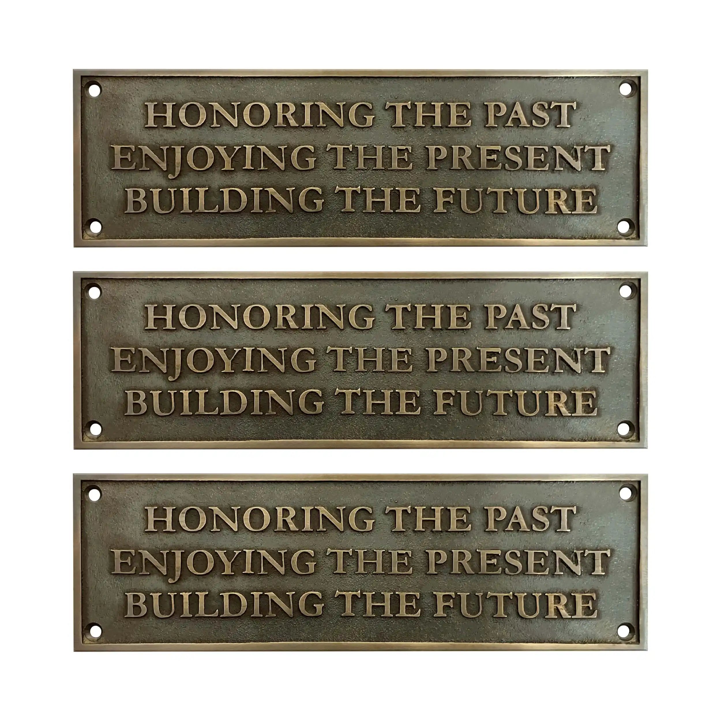 Three bronze plaques with engraved text on a white background