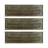 Three bronze plaques with engraved text on a white background