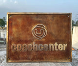 Rust-colored sign with 'coachcenter' logo on a stone surface