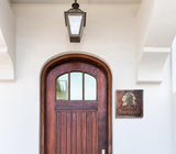 Wooden door with glass panels and a hanging light fixture on a white wall.