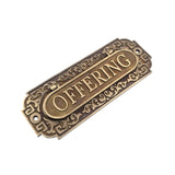 An antique bronze metal sign with ornate scrollwork borders and a central oval plaque, shown on a plain white background.