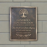 Decorative plaque with tree design and engraved text on a gray wall.