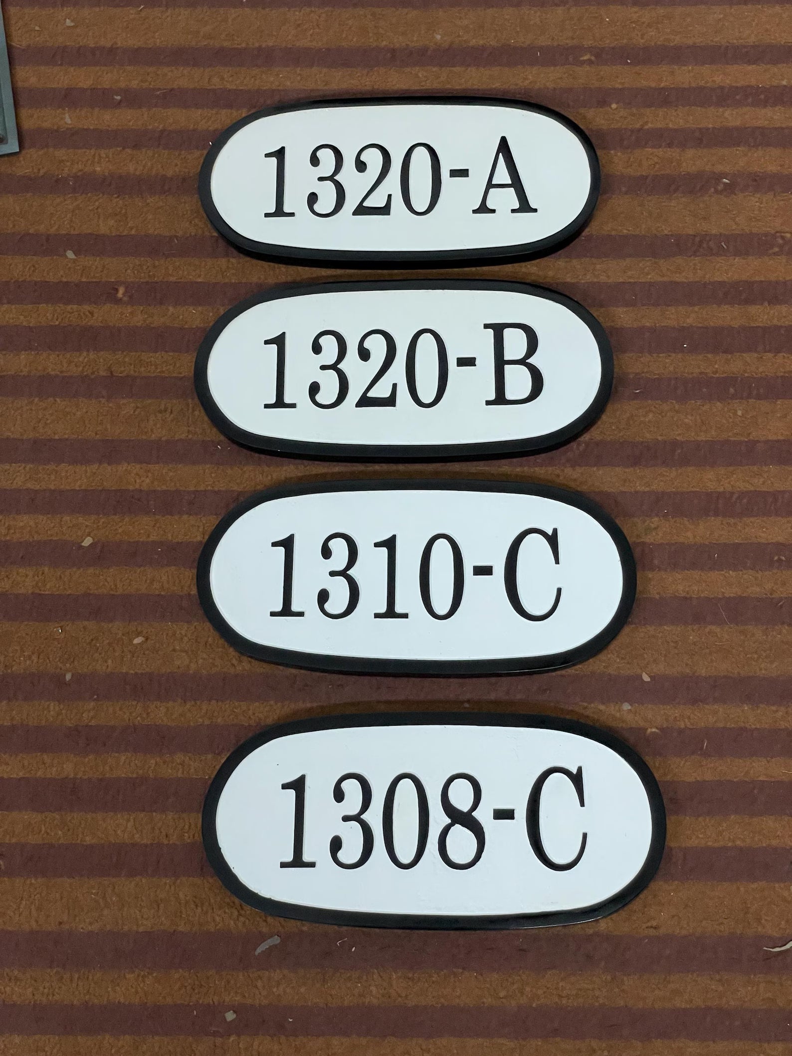 Four oval address plaque with text on a striped brown background
