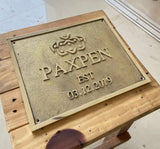 Metal plaque with 'PAXPEN' branding and establishment date on a wooden surface