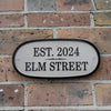 House number sign on a brick wall with 'EST. 2024 ELM STREET' text.