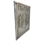 Bronze sign with 'The Trail' and tree design on a white background