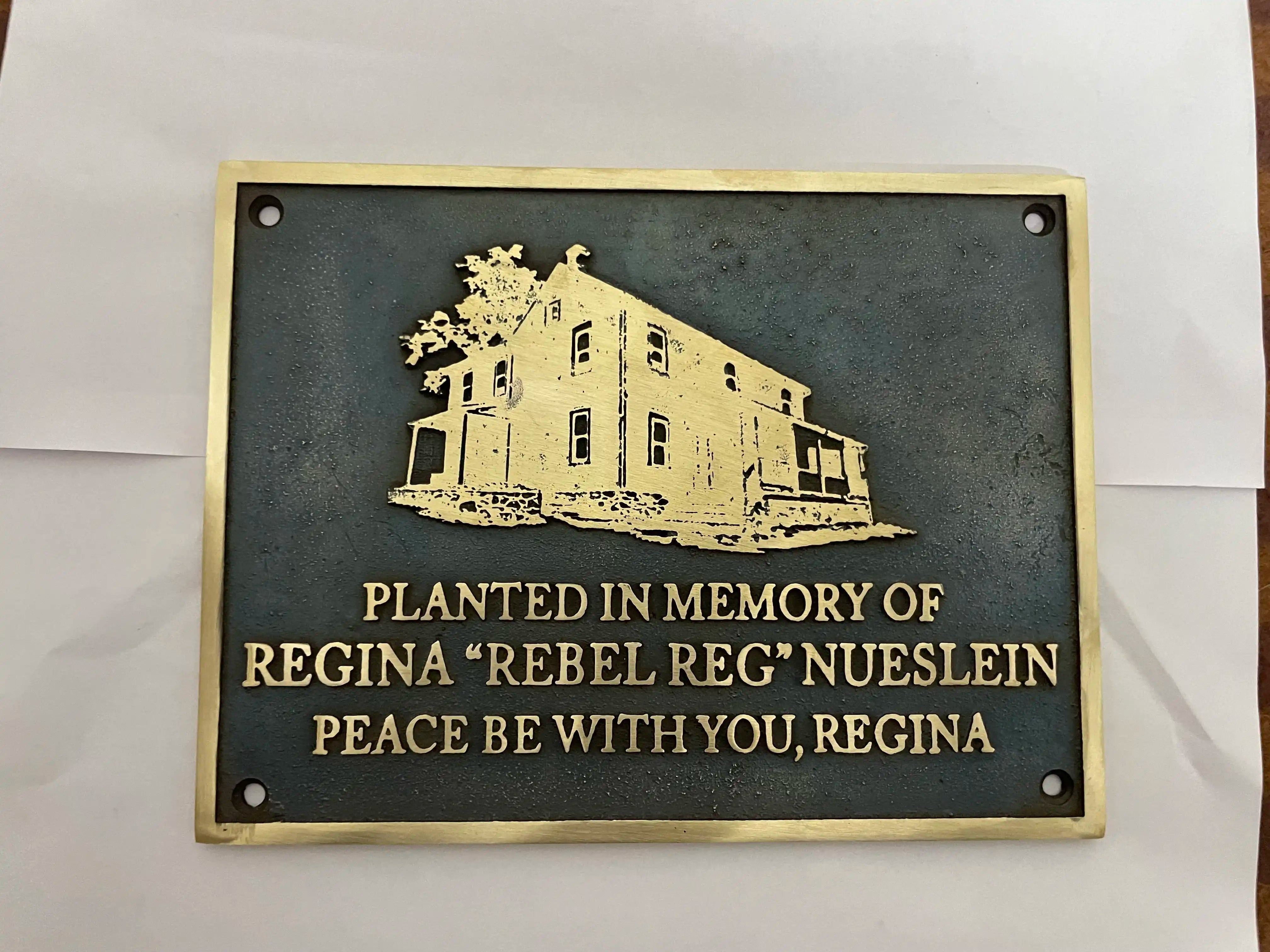 Bronze plaque with engraved text and illustration on a white background