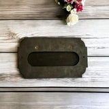 Rectangular metal letterbox on a wooden surface with flowers in the corner