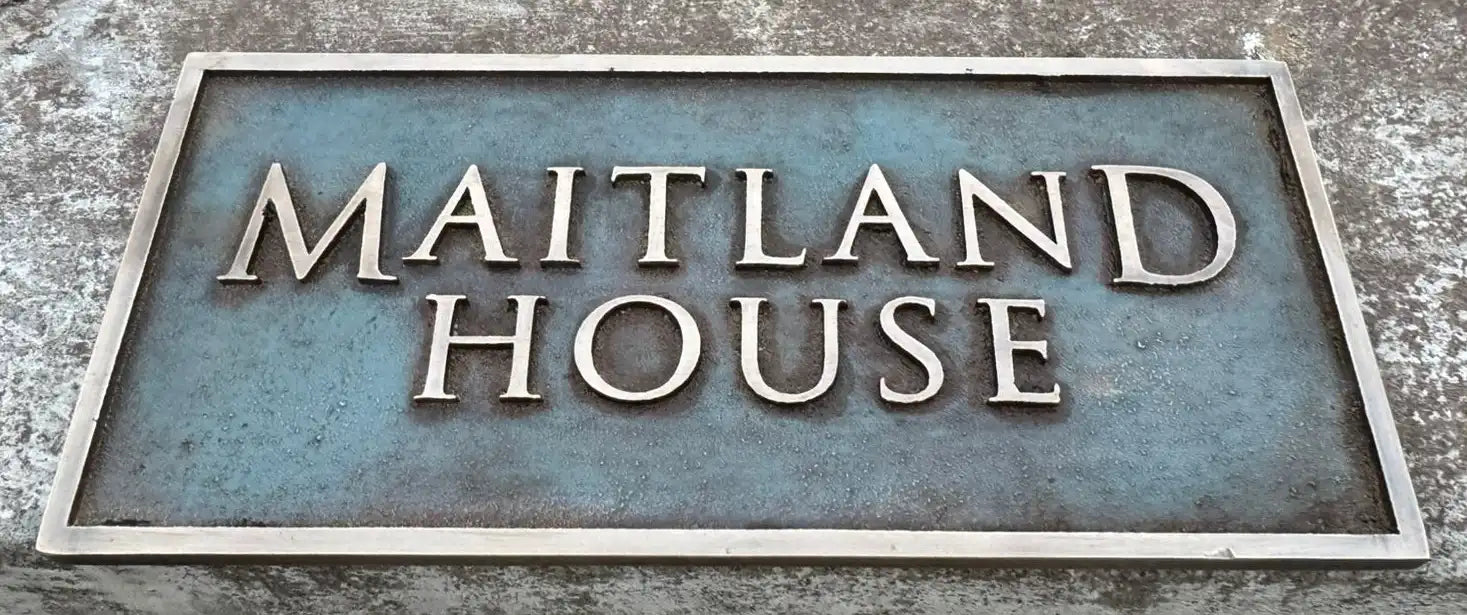 Bronze address sign with 'MAITLAND HOUSE' text on a textured background