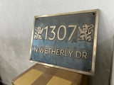 Metal address sign with number '1307' and text 'N WETHERLY DR' on a textured wall.