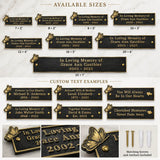 A product infographic showing multiple black metal memorial plaques in different sizes, with gold engraved text and decorative gold leaf and heart motifs. The image includes sections labeled available sizes, custom text examples, and close-up views of the plaques with mounting hardware on a light marble background.