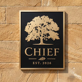 Bronze plaque address sign with tree design and 'CHIEF EST. 2026' text on a stone wall.