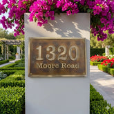 Bronze Address sign on a wall with pink flowers above it