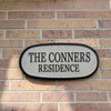 Enameled metal sign with 'The Conners Residence' on a brick wall.