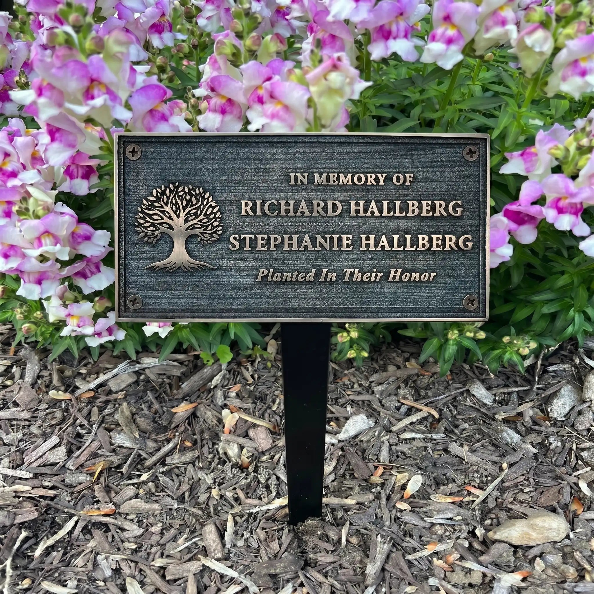 Bronze Memorial plaque in a garden setting with flowers.