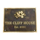 Bronze metal sign with floral design and text 'The Cliff House Est. 2000' on a white background