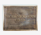A cast bronze plaque with the inscription 'THE FOUNDER'S ROOM EST. 2011' in capital letters, set against a light background.