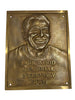Bronze plaque with a smiling face and engraved text 'Jack Wood Memorial Interview Room' on a white background